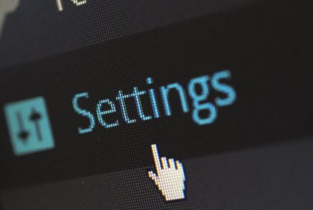 A close-up photo of a computer screen showing the settings button with a cursor hovering over it.