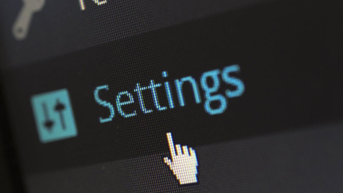 A close-up photo of a computer screen showing the settings button with a cursor hovering over it.